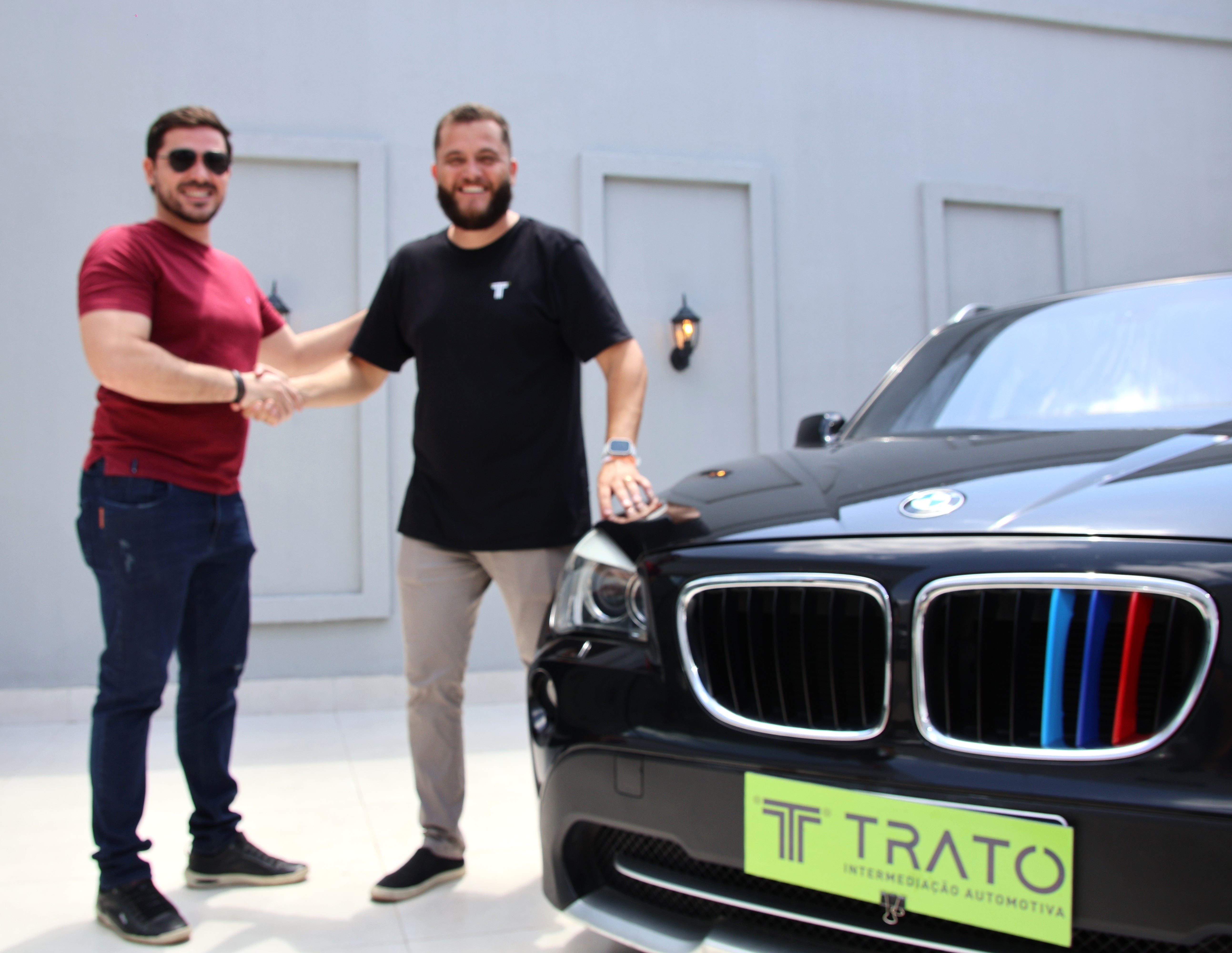 Cliente e consultor da Trato ao lado de um veículo BMW